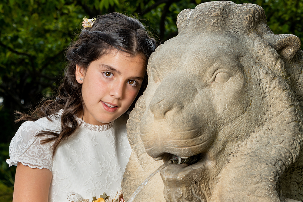Sara junto a la fuente del león, en una preciosa imagen de su reportaje de primera comunión, realizada por Agustín Pacheco