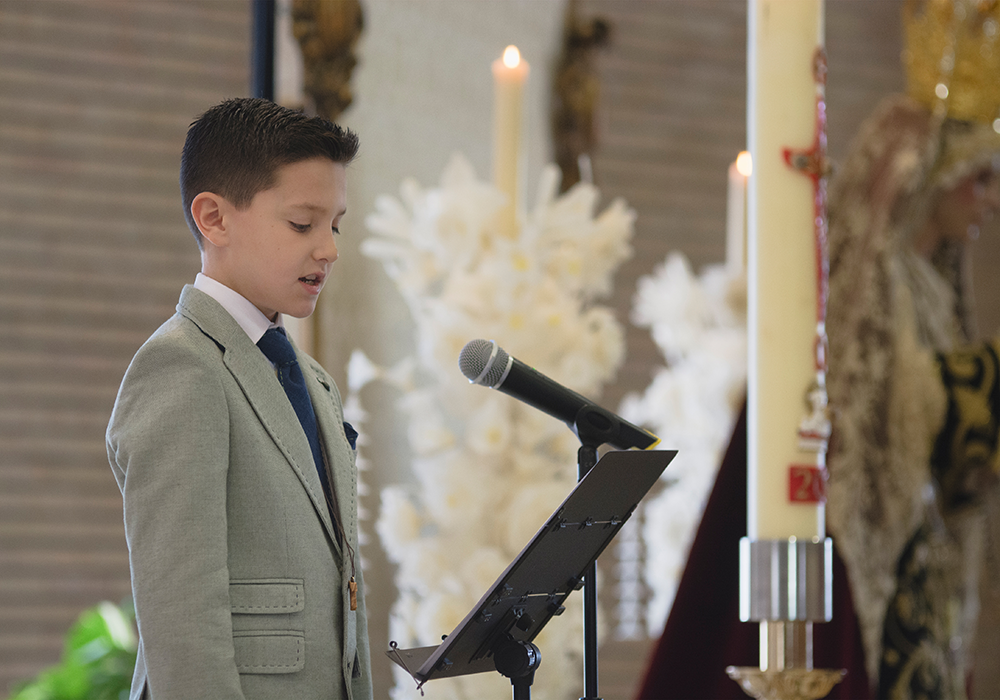 Niño en su primera comunión, reportaje fotográfico en iglesia, mientras realiza una lectura
